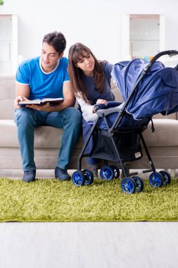 Bebekleri bebek arabasında oturan genç ebeveynler.