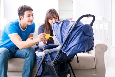 Bebekleri bebek arabasında oturan genç ebeveynler.