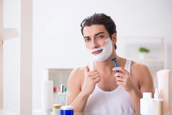 Young handsome man shaving early in the morning at home