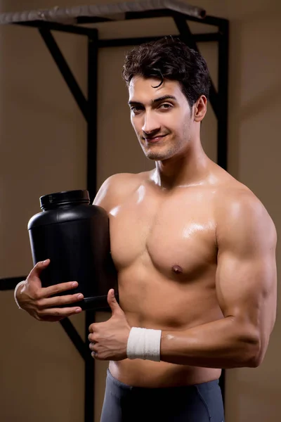Homem com suplementos nutricionais no ginásio desportivo — Fotografia de Stock