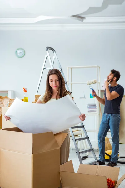 Familia joven desempacando en casa nueva con cajas — Foto de Stock