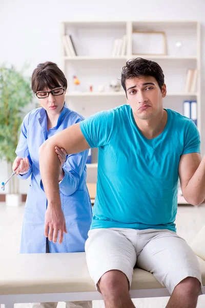 Doktor çekiçle sinir reflekslerini kontrol ediyor