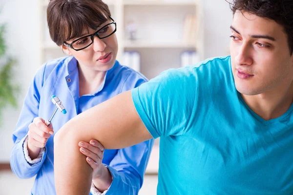 Doktor çekiçle sinir reflekslerini kontrol ediyor