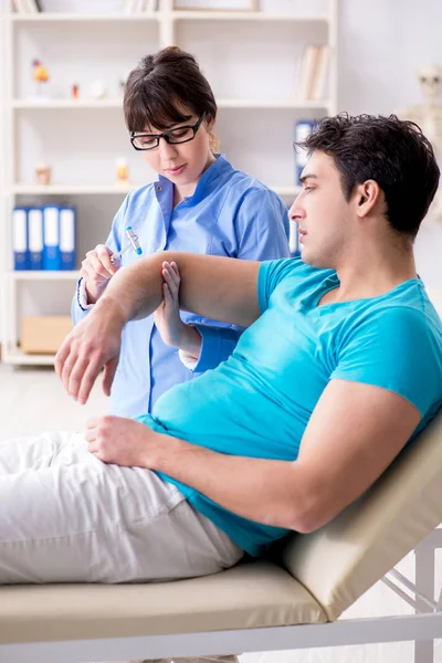 Doktor çekiçle sinir reflekslerini kontrol ediyor