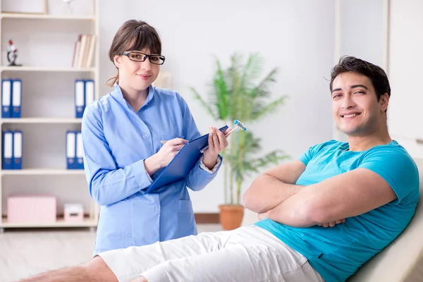 Doktor çekiçle sinir reflekslerini kontrol ediyor