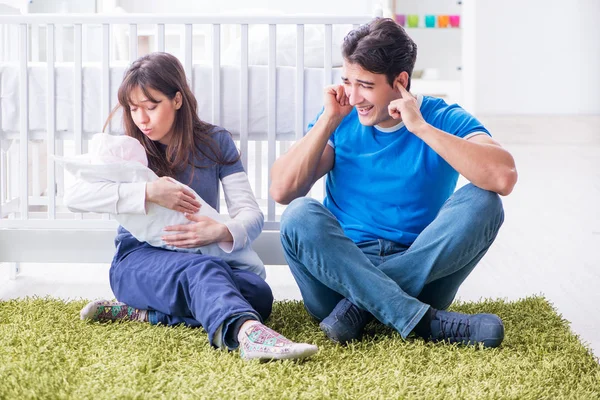 Yeni doğmuş bebekleriyle halıda oturan genç ebeveynler. 
