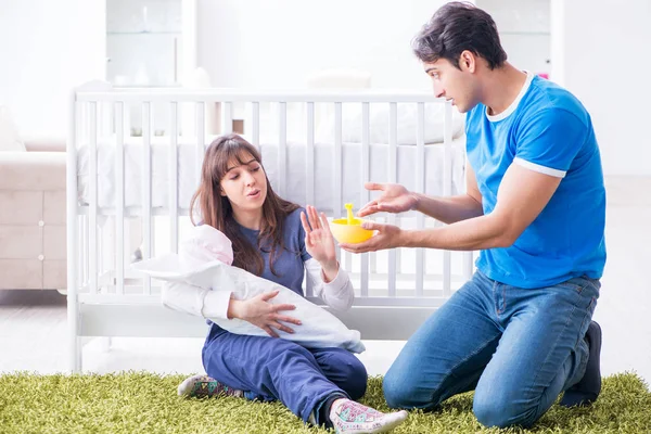 Jonge ouders met hun pasgeboren baby zittend op het tapijt — Stockfoto