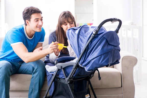 Bebekleri bebek arabasında oturan genç ebeveynler.