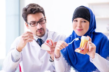 Diş hekimi ve asistanı yeni diş implantı üzerinde çalışıyor.