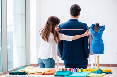 Profesyonel terzi resmi kıyafet için ölçü alıyor.