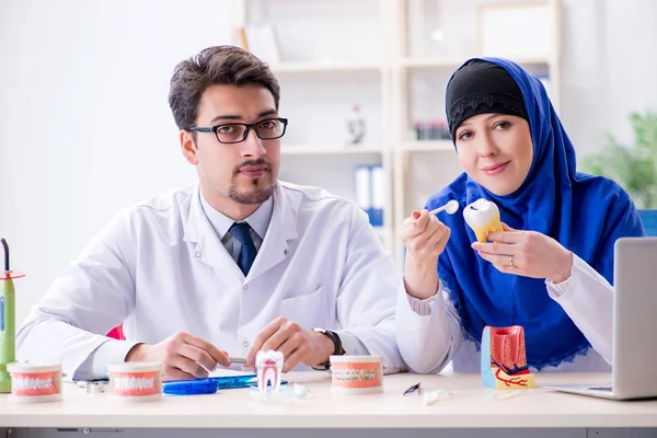 Diş hekimi ve asistanı yeni diş implantı üzerinde çalışıyor.