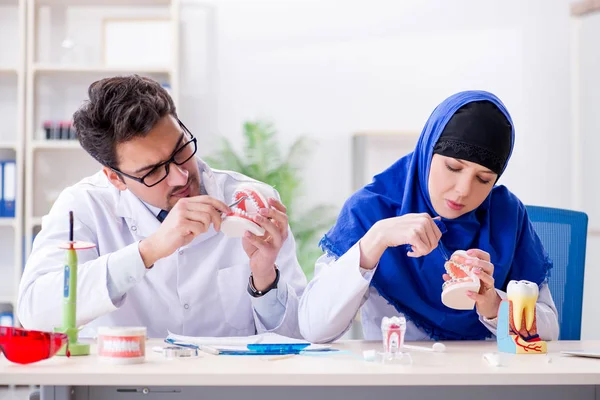 Diş hekimi ve asistanı yeni diş implantı üzerinde çalışıyor.