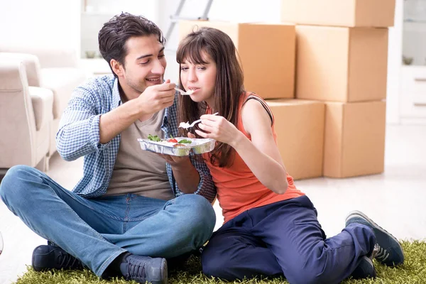 Mladá rodina jíst jídlo v novém bytě po přestěhování v — Stock fotografie