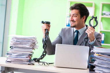 Çalışan, iş yükü nedeniyle masasına zincirlenmiş.