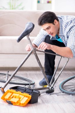 Evde bisiklet tamir eden genç bir adam.