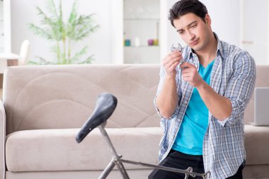 Evde bisiklet tamir eden genç bir adam.