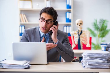 İskeletle çalışan bir iş adamı.