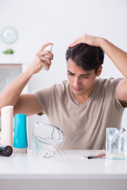 Genç yakışıklı adam aynaya bakıyor. 