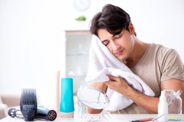 Genç yakışıklı adam aynaya bakıyor. 