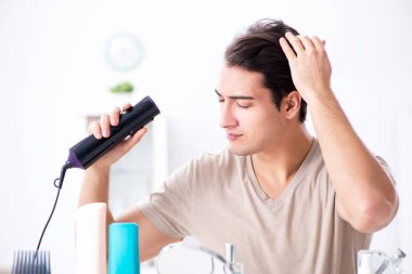 Genç yakışıklı adam aynaya bakıyor. 