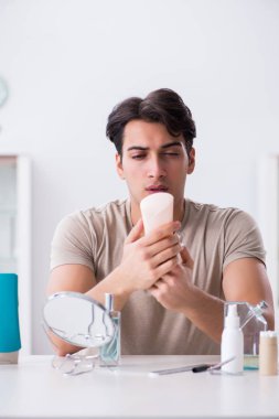 Genç yakışıklı adam aynaya bakıyor. 