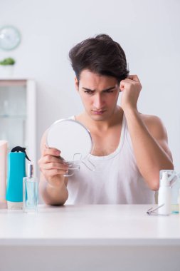 Genç yakışıklı adam aynaya bakıyor. 