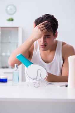 Genç yakışıklı adam aynaya bakıyor. 