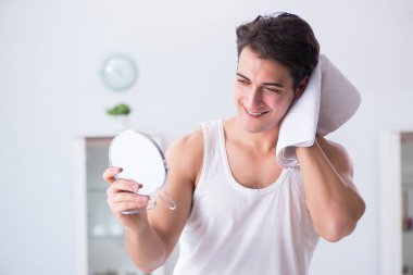 Genç yakışıklı adam aynaya bakıyor. 