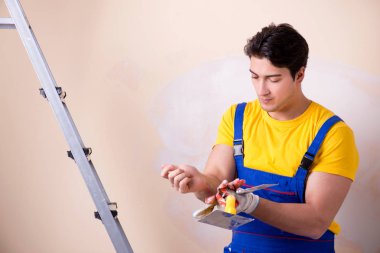 Duvara alçı yapıştıran genç müteahhit.