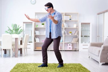 Evde sanal gerçeklik gözlüklü bir adam oynuyor.