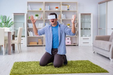 Evde sanal gerçeklik gözlüklü bir adam oynuyor.