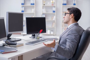Birçok ekranın önünde oturan bir iş adamı