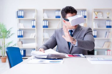 Ofiste sanal gerçeklik gözlüklü bir iş adamı var.