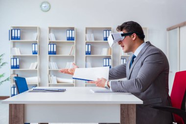 Ofiste sanal gerçeklik gözlüklü bir iş adamı var.