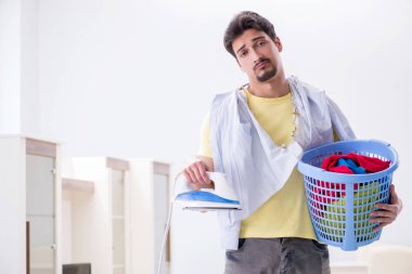 Yakışıklı koca evde kıyafet ütülüyor.