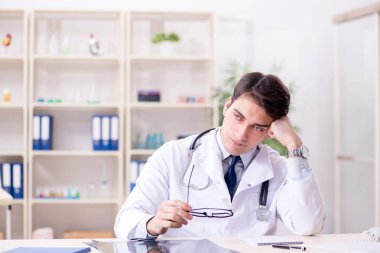 Genç doktor ofiste oturuyor.