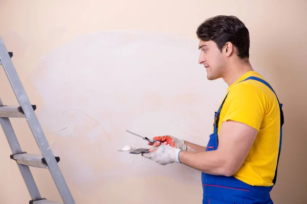 Empregado jovem empreiteiro aplicando gesso na parede — Fotografia de Stock