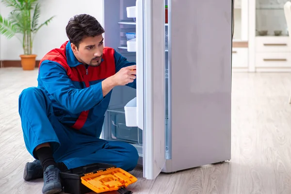 Professional contractor repairing broken fridge