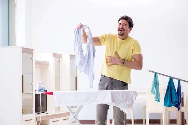 Красивый муж, который гладит дома одежду. — стоковое фото
