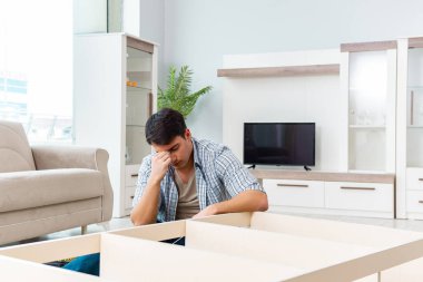 Adam evde mobilya montajı yapıyor.