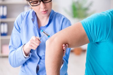 Doktor çekiçle sinir reflekslerini kontrol ediyor