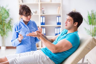 Doktor çekiçle sinir reflekslerini kontrol ediyor