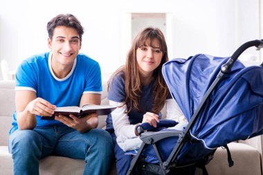 Bebekleri bebek arabasında oturan genç ebeveynler.