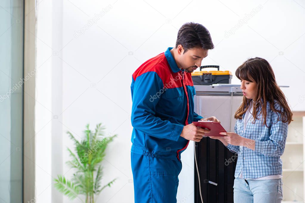 Man repairing fridge with customer