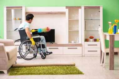 Tekerlekli sandalyedeki engelli adam temizlik yapıyor.