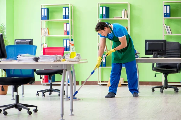 Masculino bonito profissional de limpeza fazendo esfregar no escritório — Fotografia de Stock