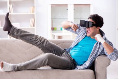 Eli yaralı bir adam sanal gerçeklik gözlüğü takıyor.