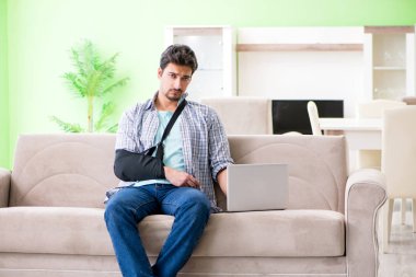 Eli yaralı genç bir öğrenci kanepede oturuyor. 