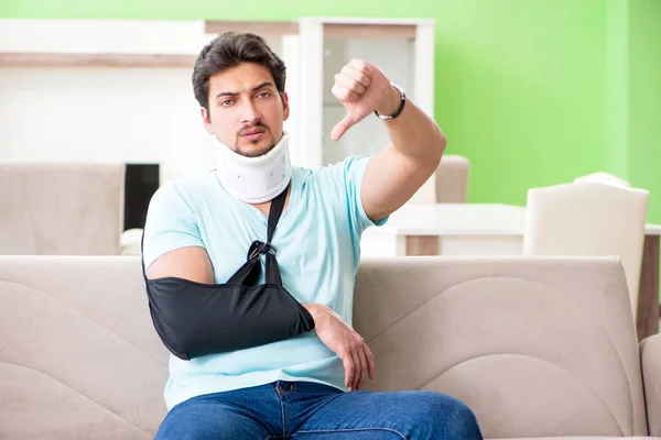 Jovem estudante com lesão no pescoço e na mão sentado no sofá — Fotografia de Stock