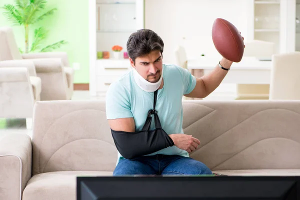 Mann mit Hals- und Armverletzung schaut American Football im Fernsehen — Stockfoto